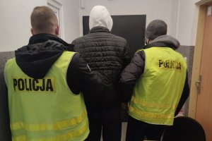 dwaj policjanci prowadzą zatrzymanego mężczyznę