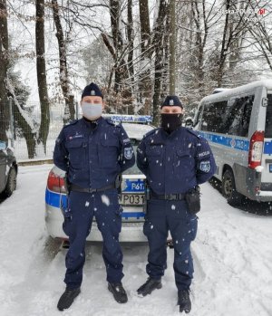 Fotografia przedstawia dwóch umundurowanych policjantów na tle radiowozu.