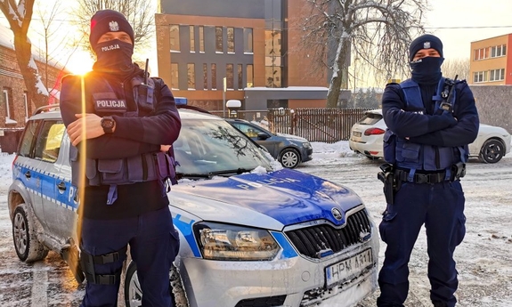 dwaj policjanci stoją przy radiowozie