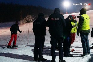 Na zdjęciu widoczni policjanci i narciarze. W tle widoczny stok