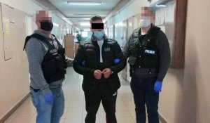 Zatrzymany mężczyzna w komendzie prowadzony przez policjantów