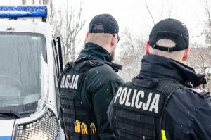 dwaj policjanci stoją obok radiowozu policyjnego