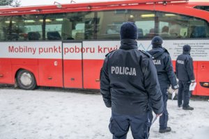 policjanci stojący w kolejce do krwiobusa