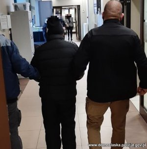 prowadzenie mężczyzny przez dwóch policjantów korytarzem komendy