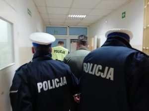 policjanci prowadzą zatrzymanego mężczyznę