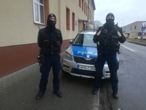 dwaj policjanci stoją przy radiowozie