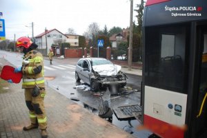 rozbity samochód stoi za autobusem miejskim po lewej stronie strażak pracujący na miejscu wypadku