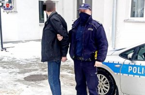 Zatrzymany włamywacz i policjant na tle radiowozu