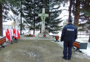policjant stoi przed pomnikiem w kształcie krzyża