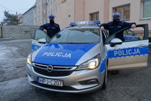 dwaj policjanci stoją przy radiowozie