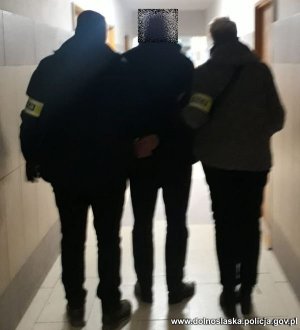 dwaj policjanci prowadzą zatrzymanego