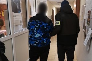 dwaj mężczyźni na korytarzu jeden na ramieniu ma opaskę z napisem policja