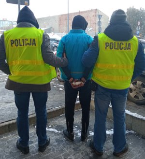 dwaj policjanci prowadzą zatrzymanego mężczyznę