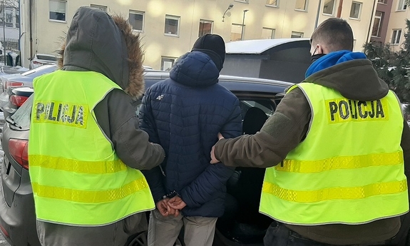 dwaj policjanci prowadzą zatrzymanego mężczyznę