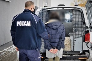 Policjant prowadzi zatrzymanego do radiowozu