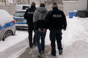 Policjanci prowadzą zatrzymanego