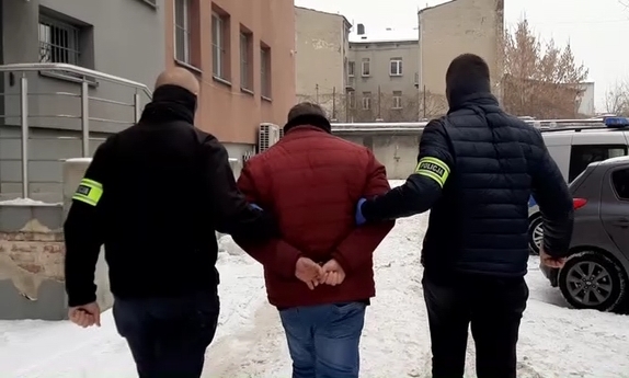 dwaj policjanci prowadzą zatrzymanego mężczyznę