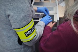 Policjant pobiera odciski palców zatrzymanej kobiety