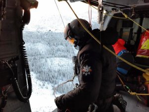 ratownik TOPR i policjant wciągają poszkodowaną do helikoptera