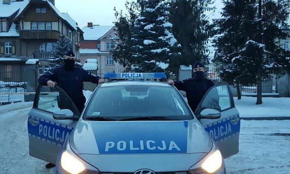 Policjanci stoją przy radiowozie