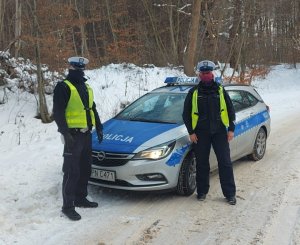 dwaj policjanci stoją przy radiowozie