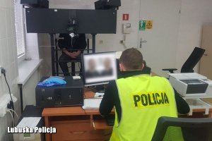 policjant fotografuje podejrzanego specjalistycznym sprzętem