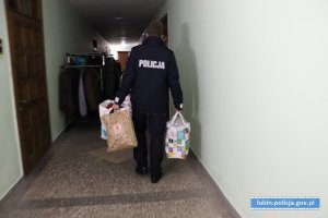 klatka bloku. policjanci niosą paczki z odzieżą