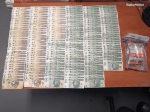 Zabezpieczona przez policjantów gotówka - banknoty rozłożone są na biurku
