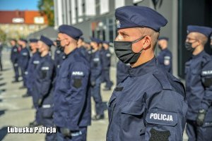 umundurowani policjanci rozstawieni stoją na placu przed budynkiem, na twarzach mają maseczki