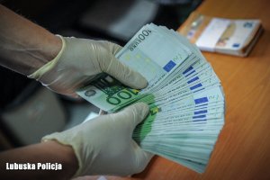 policjant trzyma w rękach plik banknotów euro
