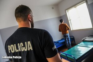 policjant pilnuje zatrzymanego mężczyznę w pomieszczeniu dla zatrzymanych