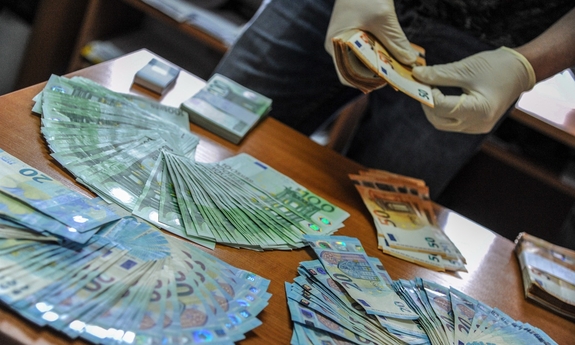 policjant liczy banknoty leżące na stole