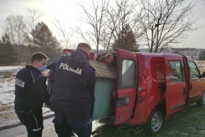 policjanci przenoszą budę dla psa do samochodu