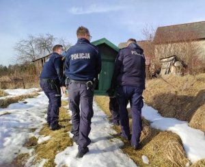 umundurowani czterej policjanci niosą budę dla psa