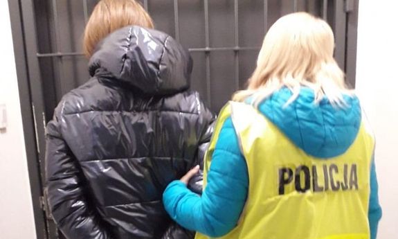 zatrzymana kobieta tyłem w asyście policjantki