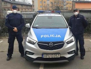 dwaj policjanci stoją przy radiowozie