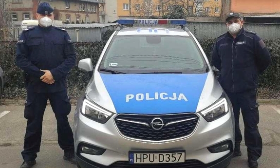 dwaj policjanci stoją przy radiowozie