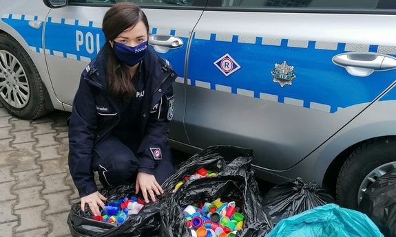 zdjęcie przedstawia policjantkę przy workach z nakrętkami