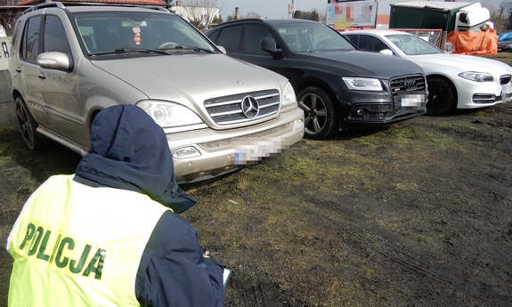 Policjant kuca przy odzyskanym samochodzie
