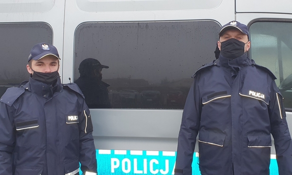dwaj policjanci stoją przy radiowozie policyjnym