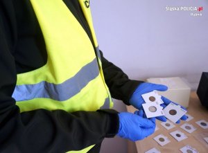 Policjant prezentuje odzyskane monety kolekcjonerskie