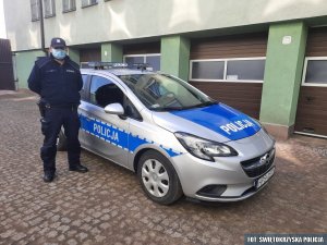 umundurowany policjant stoi przy radiowozie
