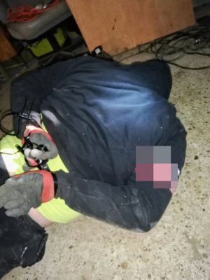 zatrzymany mężczyzna leży na ziemi z unieruchomionymi rękoma trzymanymi za plecami