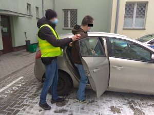 Policjant doprowadza zatrzymanego 33-latka do radiowozu