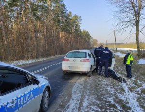 Policjanci stoją w pobliżu zatrzymanego seata, na ziemi leży mężczyzna, który uciekał przed policjantami, a obok policjantka