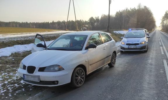 Radiowóz stoi za stojącym białym seatem