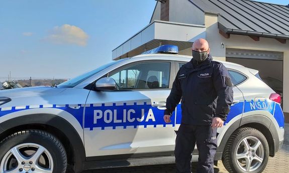 policjant stoi przy radiowozie