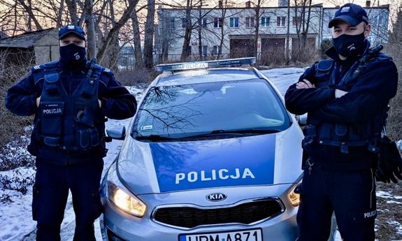 dwaj policjanci stoją przy radiowozie