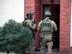 dwaj uzbrojeni funkcjonariusze stoją przed budynkiem