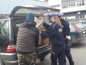 Policjanci przenoszą do samochodu worki z nakrętkami